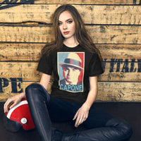 Model wearing a black unisex t-shirt featuring a graphic design inspired by Capone, on a rustic wooden background.