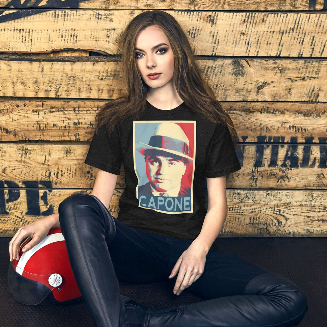 Model wearing a black unisex t-shirt featuring a graphic design inspired by Capone, on a rustic wooden background.